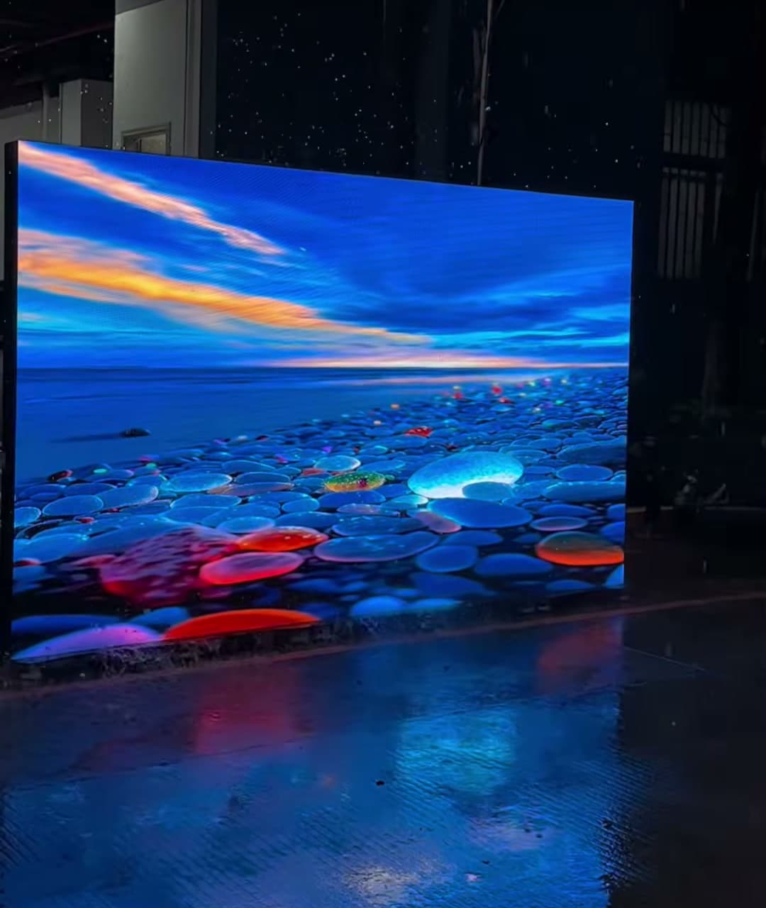 Mehrere gekoppelte LED-Aufsteller mit Naturmotiv im Regen und Spiegelung auf nassem Boden