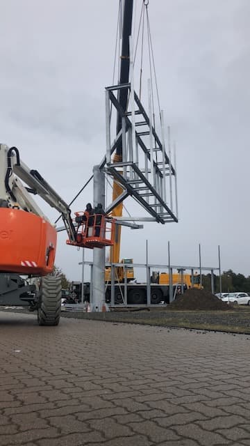 Monteure sichern den Stahlrahmen vom Arbeitskorb aus am Mast