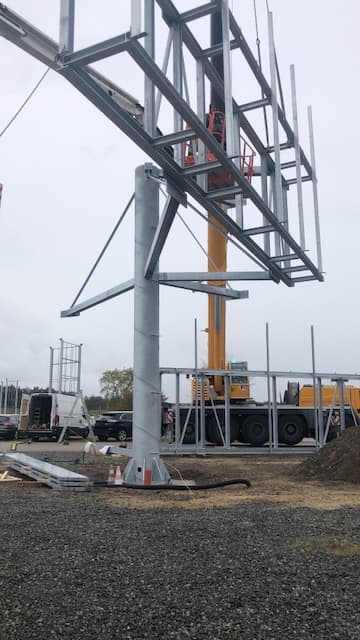 Verzinkter Stahlrahmen wird per Kran auf die zentrale Säule gesetzt