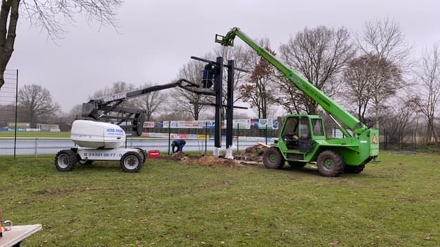 Stahlmast der Anzeigetafel wird mit Teleskoplader und Hebebühne am Sportplatz aufgestellt