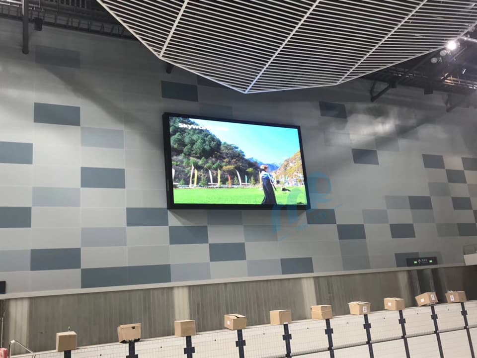 LED-Tafel an der Wand einer Sporthalle mit Landschaftsmotiv über Sitzplätzen