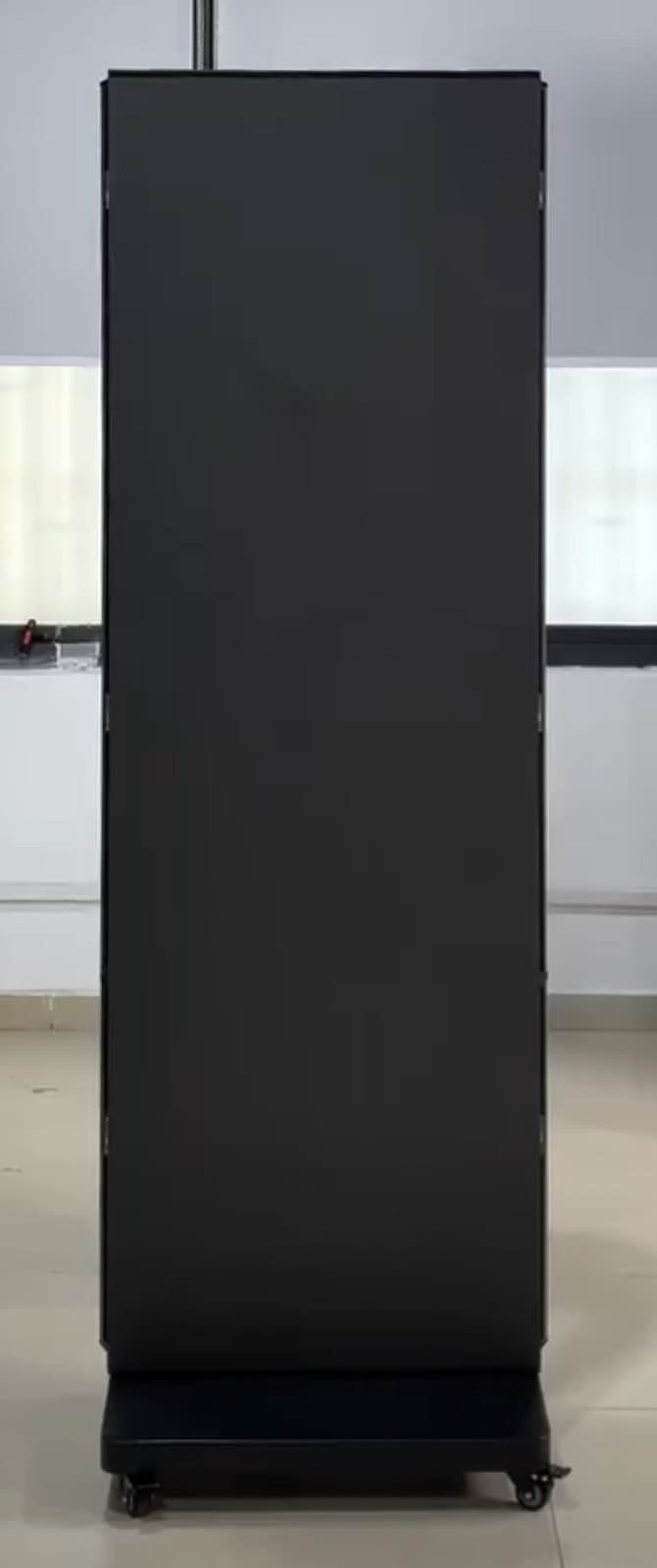 Schmaler mobiler Aufsteller mit dunkler Fläche und vollständig sichtbarem Rollfuß. Standbild aus einem Video.