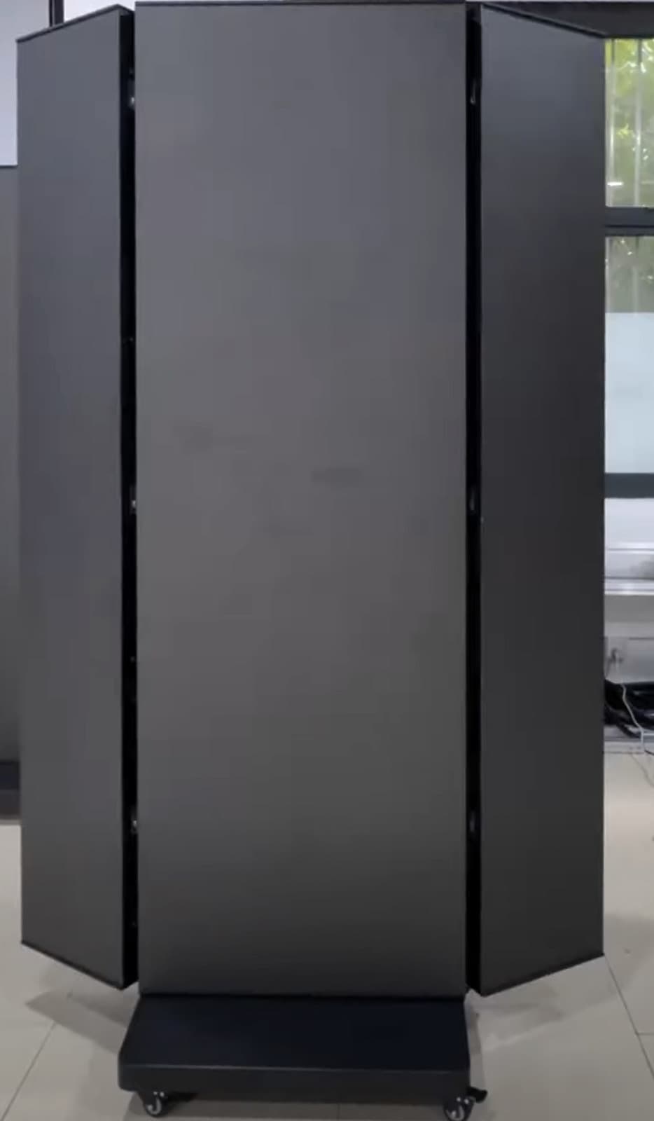 Vorderseite eines nicht ganz aufgeklappten LED-Faltposters mit dunkler Bildfläche, schräg gestellten Seitenflächen und Rollfuß. Standbild aus einem Video.