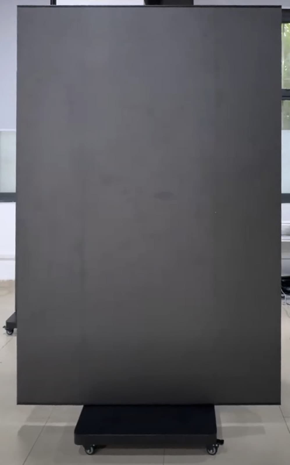Breiter LED-Aufsteller mit vollständig geöffneter dunkler Fläche auf einem Rollfuß. Standbild aus einem Video.