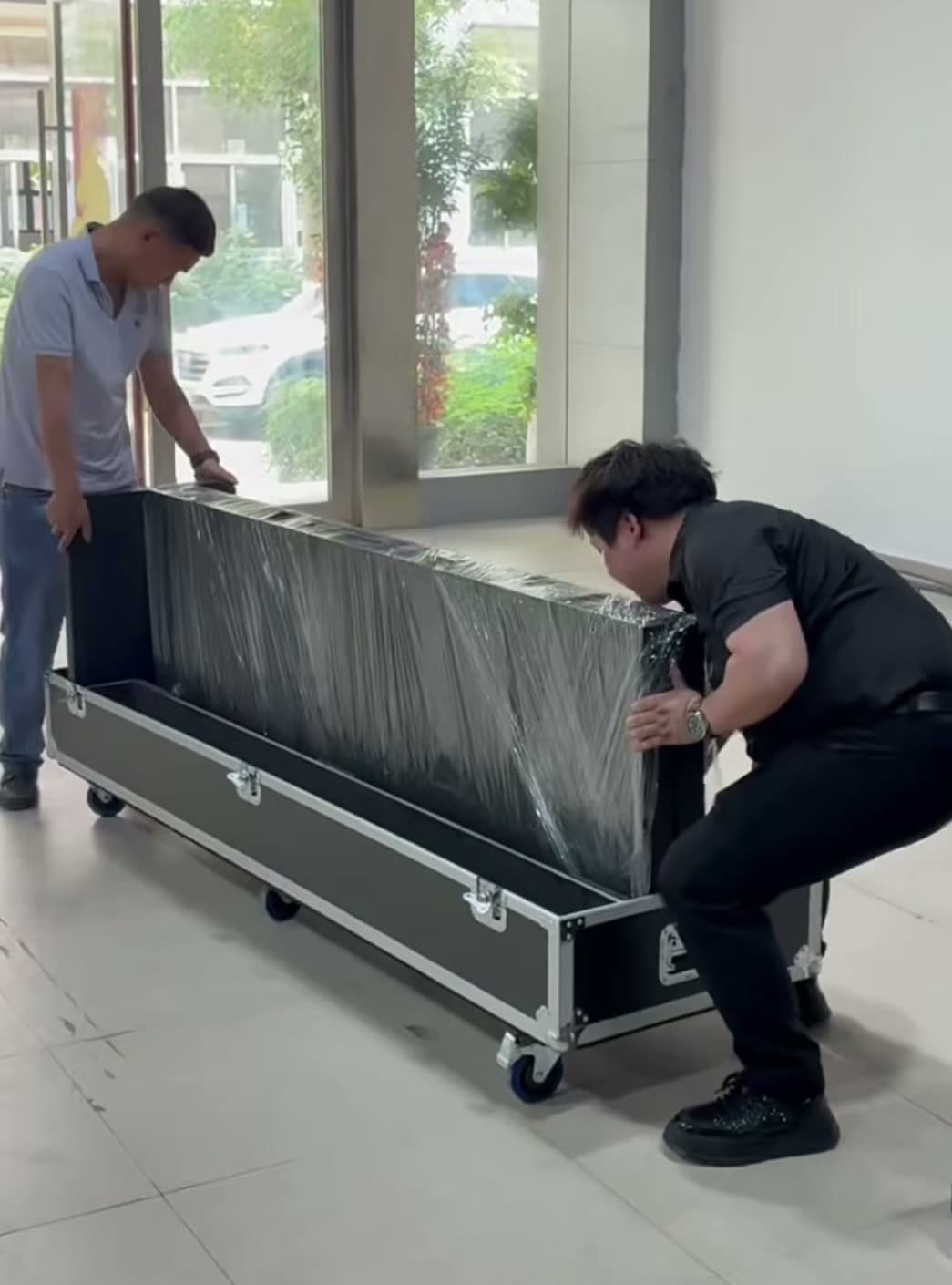 Zusammengefalteter LED-Aufsteller beim Einsetzen in ein Flightcase durch zwei Personen